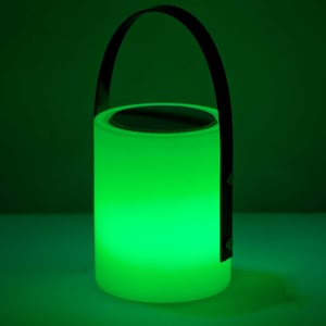 A green, cylindrical speaker lamp with a black handle and a metallic top, emitting glowing light.