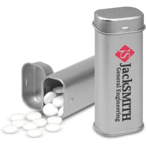 A silver tin containing white mints, with the tin slightly open and some mints spilling out.