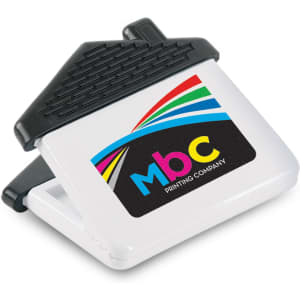 A white magnetic clip shaped like a house with a black top and a multicoloured logo.