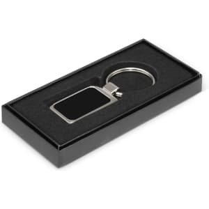 A metal key ring with a rectangular blank surface for laser etching, presented in a sleek black gift box.