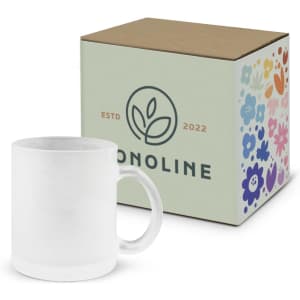 A white coffee mug next to a decorative box featuring floral designs and a logo.