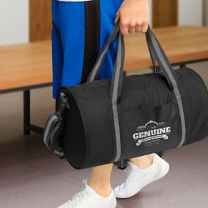 A black duffle bag with gray straps featuring "Genuine" branding is being held by a person.