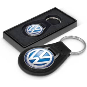 A round leather key ring in black with a circular logo, displayed in a sleek black box.