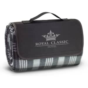 A folded picnic blanket in grey and black, featuring a logo, with a handle for easy carrying.