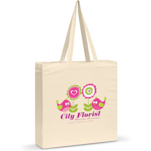 A cream-coloured cotton shoulder tote featuring a colourful floral and bird design, along with a logo.