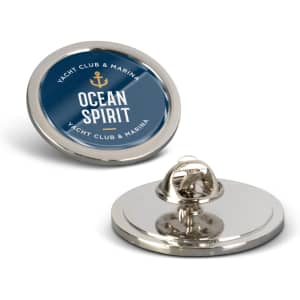 A round, large lapel pin with a shiny silver finish and a blue design featuring a logo.