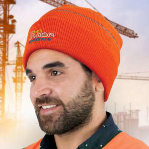 An orange hi-visibility beanie worn by a person, featuring a logo and set against a construction background.
