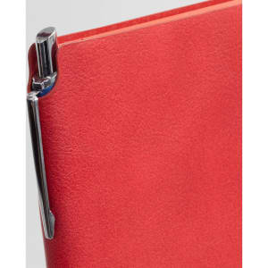 A red notebook with a shiny pen attached to the side. The notebook has a sleek, smooth cover.