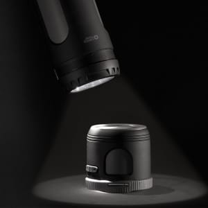 A black Swiss Peak 4-in-1 speaker illuminated by a flashlight, showcasing its sleek design and functionality.