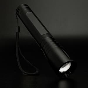 A Swiss Peak 10W Cree Torch features a sleek black design with a textured grip and a wrist strap for easy handling.