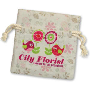 A small cotton gift bag in beige with floral patterns and a logo featuring colourful birds and flowers.
