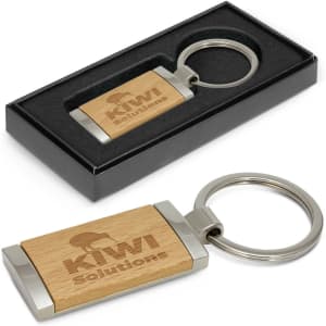 A wooden key ring with a silver keychain, presented in a black box. The wood features a logo.