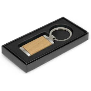 A wooden key ring with a metal attachment, presented in a black gift box with a foam insert.