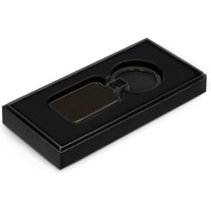 A black Astina key ring displayed in a black gift box with a soft interior.
