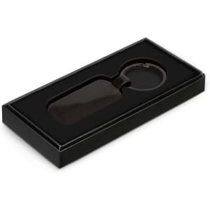 A Taurus key ring in a black box with an elegant design, featuring a sleek, dark-hued key ring.