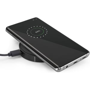 A sleek black wireless charger with a smartphone placed on top, displaying a charging status of 63%.
