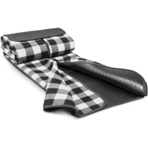 A black and white checked picnic blanket, rolled up with a black leather strap and a waterproof backing.