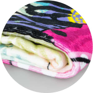 A rolled-up Picasso Beach Towel featuring vibrant colors and abstract patterns.