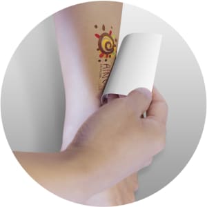 A hand applying a Temporary Tattoo Foil on an arm, featuring a colorful design.
