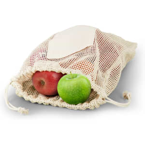 A cotton produce bag in natural colour, filled with red and green apples, resting on a white background.