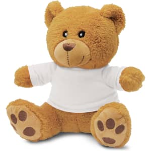 A plush teddy bear in a light brown colour, wearing a plain white t-shirt, with soft features and paw prints.