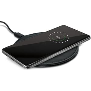A wireless charger with a smartphone placed on top, displaying a charging indicator on the screen.