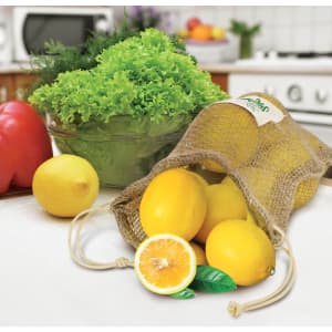 A jute net produce bag filled with lemons, accompanied by a cut lemon and a bowl of greens.