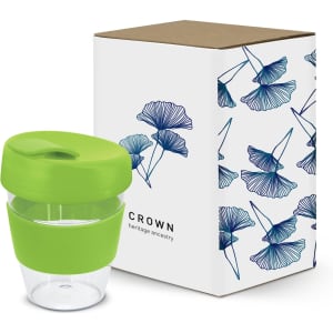 A drink bottle with a clear body and a green lid, displayed with a decorative box featuring floral patterns.