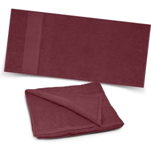 A maroon beach towel with a textured surface and a folded section, featuring a subtle logo.