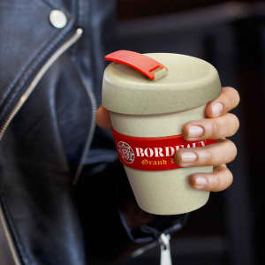 A drink bottle in a light green colour with a red band and a red lid. It features a logo.