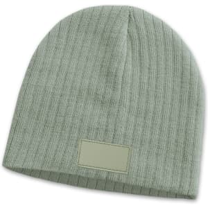 A green cable knit beanie featuring a patch. The design is textured and fitted for warmth.