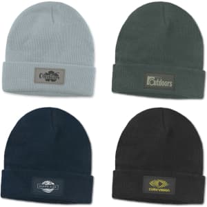 Four beanies in light grey, dark green, navy blue, and black, each featuring a different logo or patch.