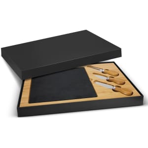 Slate cheese board in a black box with bamboo tray and three wooden-handled cheese knives.