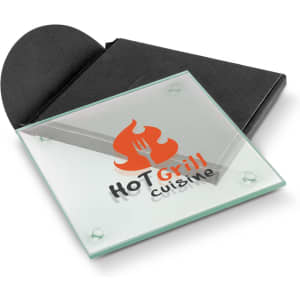 A square glass coaster in green, featuring a logo, packaged in a black envelope.