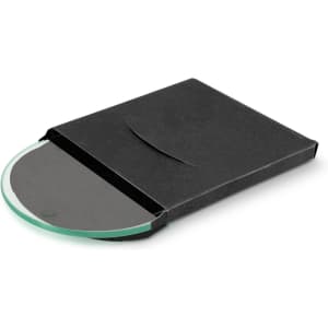 A round glass coaster in a sleek black packaging, featuring a smooth green surface.