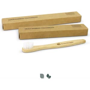 A bamboo toothbrush with a light brown handle and white bristles, placed beside two cardboard boxes.