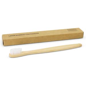 A bamboo toothbrush in natural colour, alongside a recyclable cardboard box. The toothbrush has white bristles.