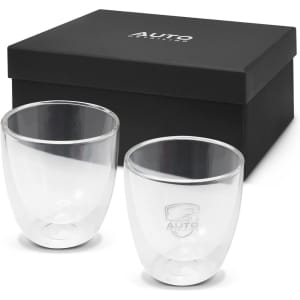 A set of two clear double wall glass cups in a black gift box, featuring a logo on each glass.