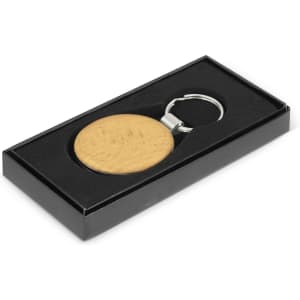 A round key ring in a wooden finish, presented in a black gift box with a silver keychain attachment.