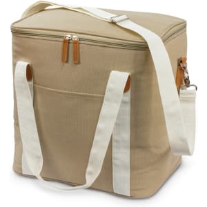 A beige canvas cooler bag with a white strap and leather accents, featuring a zip closure and side pocket.