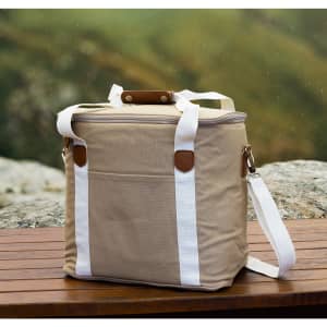 A tan canvas cooler bag with white straps and a brown handle, featuring a side pocket.