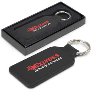 A rectangular black leather key ring with a metal ring, presented in a black box. It features a logo.