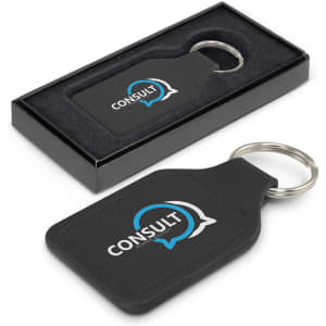 A square black leather key ring in a box, featuring a round metal key chain and a logo design.