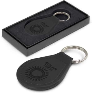 A round black leather key ring held in a black gift box, featuring a logo and silver keyring attachment.