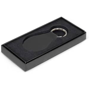 A round leather key ring in a black gift box with a soft interior. The key ring features a silver metal ring.