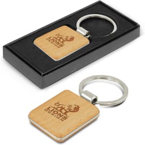 A square wooden key ring with a shiny metal ring, displayed in a black box.