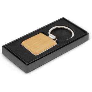 A square wooden key ring with a metal ring, presented in a black gift box with a velvet-like interior.