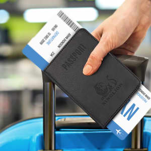 A black passport wallet holding travel documents, resting on the handle of a suitcase. It features a logo.