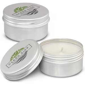 A silver tin container with a lid, featuring a white citronella candle inside. The container has a logo.