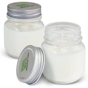 Two glass jars of a white scented candle, each with a silver metal lid and a brand logo on the top.
